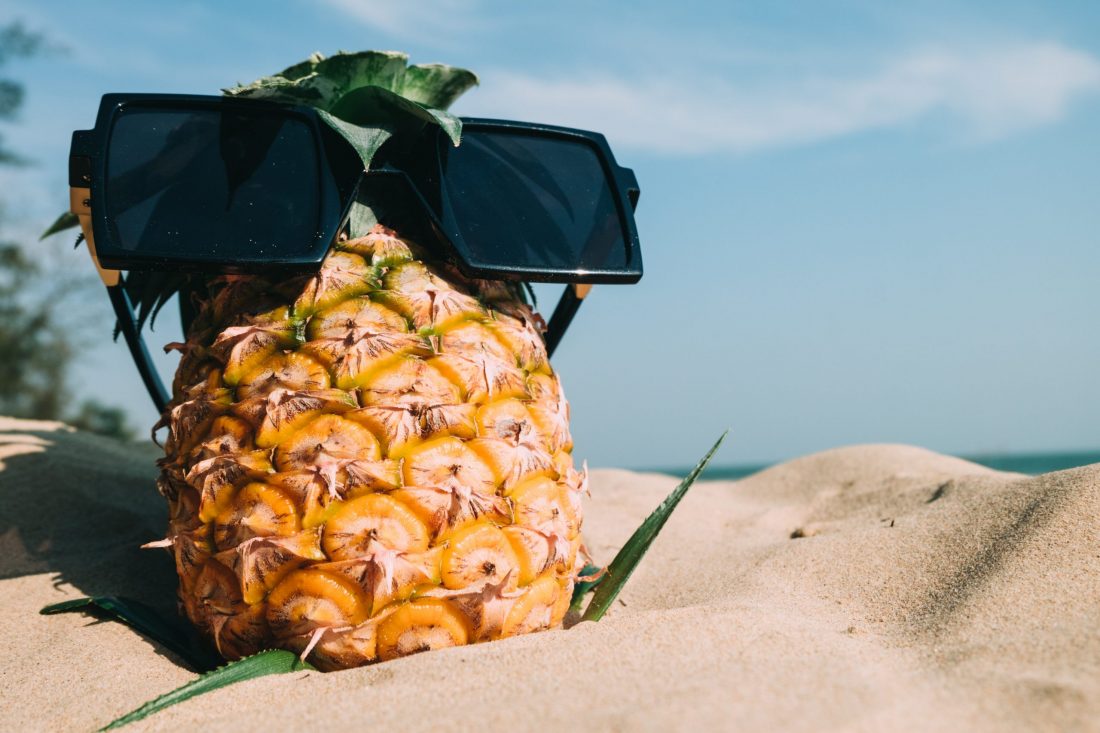 un ananas sur la plage avec des lunettes de soleil, de quoi célébrer l'été au soleil