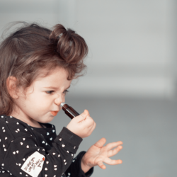 L'image représente une petite fille en train de sentir une huile essentielle