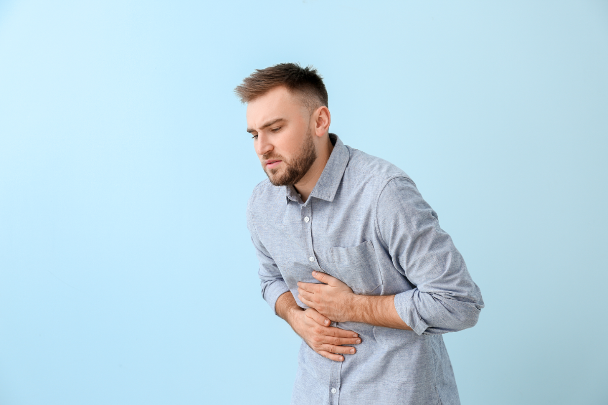 L'image représente un homme plié en deux qui souffre de douleurs liées à la gastro.