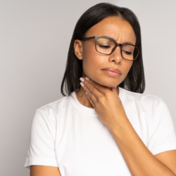 Une personne souffrant d'une angine, qui se tient la gorge.