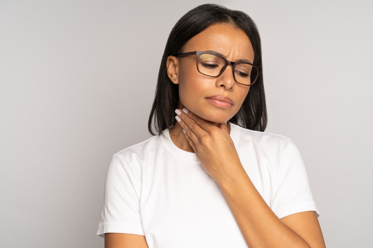 Une personne souffrant d'une angine, qui se tient la gorge.