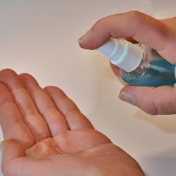 L'image représente une main qui est sur le point de déposer du gel hydroalcoolique dans l'autre main. La main droite tient un flacon pompe de gel hydroalcoolique