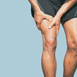 Iemand die last heeft van kramp in de dij, die het been vasthoudt na een fysieke inspanning.