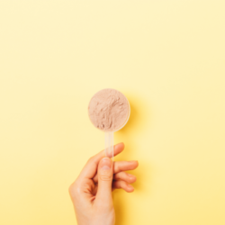 l'image représente une scoop de protéine en poudre, tenu par une main, sur un fond jaune