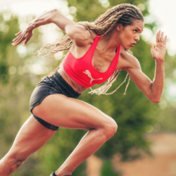 Athlète féminine en plein sprint illustrant la puissance musculaire et l'importance des protéines pour la performance sportive.