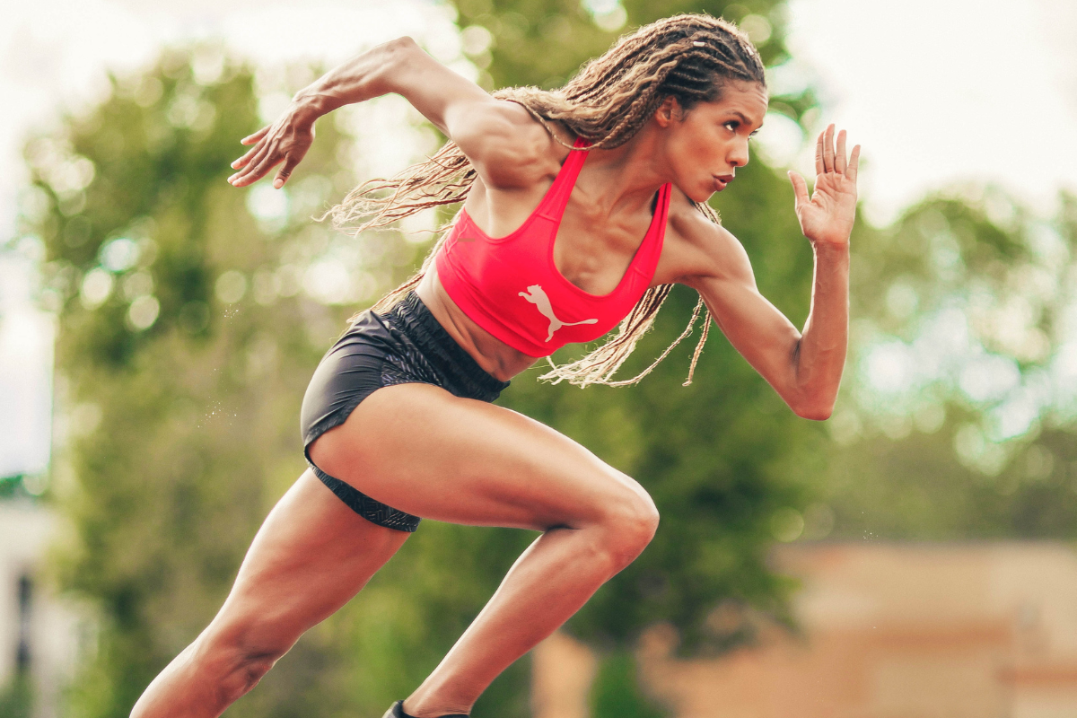 Athlète féminine en plein sprint illustrant la puissance musculaire et l'importance des protéines pour la performance sportive.