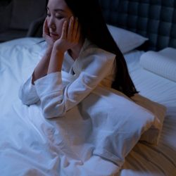 L'image représente une personne assise dans son lit ayant du mal à trouver le sommeil. troubles du sommeil