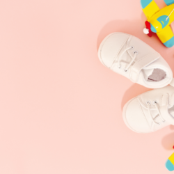 Que mettre dans sa trousse homéopathique pour la maternité. L'image représente des chaussures de bébé ainsi que des jouets, sur un fond rose.