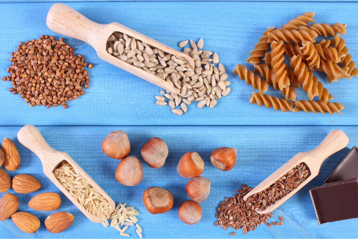 Une variété d'aliments riches en fibres : graines de tournesol, pâtes complètes, sarrasin, amandes, riz complet, noisettes, graines de lin et chocolat noir. Ces aliments illustrent l'importance des fibres alimentaires dans notre alimentation quotidienne, contribuant à une meilleure santé digestive, à la régulation de la glycémie et à la prévention de diverses maladies.