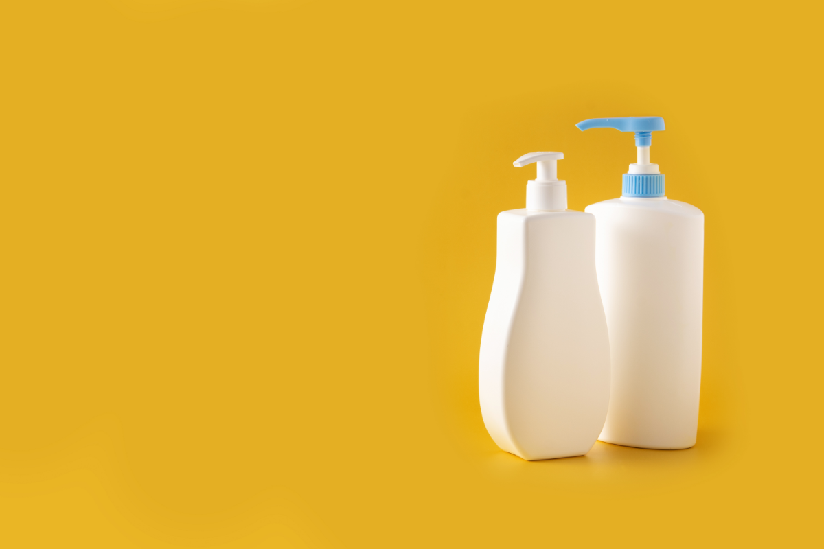 Deux flacons de produits cosmétiques sans marque, un avec un distributeur à pompe et l'autre avec un pulvérisateur, posés sur un fond uni jaune. Les flacons sont blancs, évoquant la pureté et la simplicité, suggérant des produits de soins bio pour bébés ou une cosmétique épurée et naturelle.