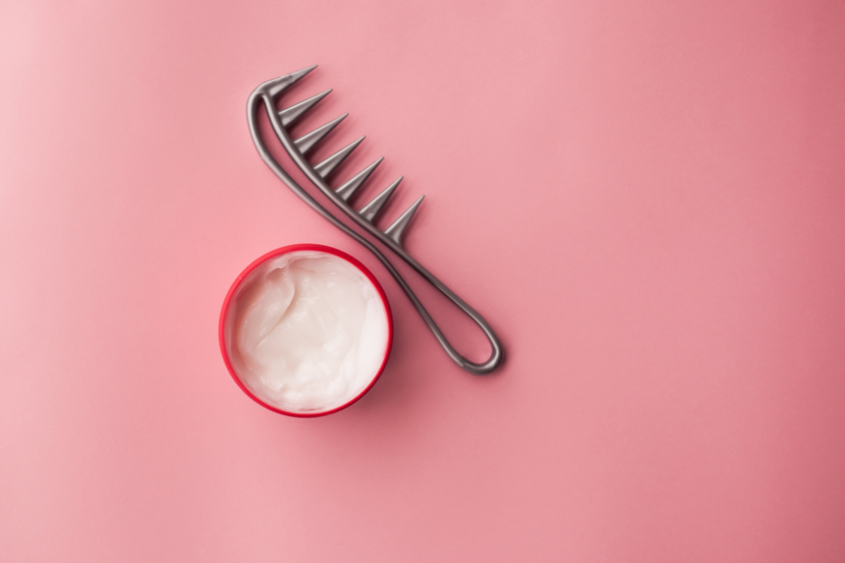 Peigne en métal et pot de masque capillaire hydratant sur fond rose – soin pour cheveux cassants et secs.
