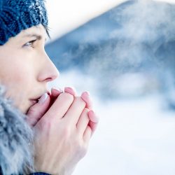 Une personne dehors en plein hiver qui essaie de se refroidir les mains, elle a probablement des engelures