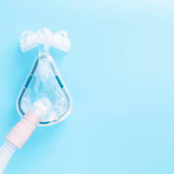 Masque CPAP pour le traitement de l'apnée du sommeil sur fond bleu, soulignant l'importance d'une thérapie efficace pour un sommeil réparateur.