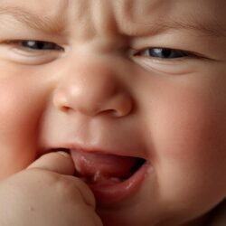Bébé grognon mettant ses doigts à la bouche à cause de la poussée dentaire