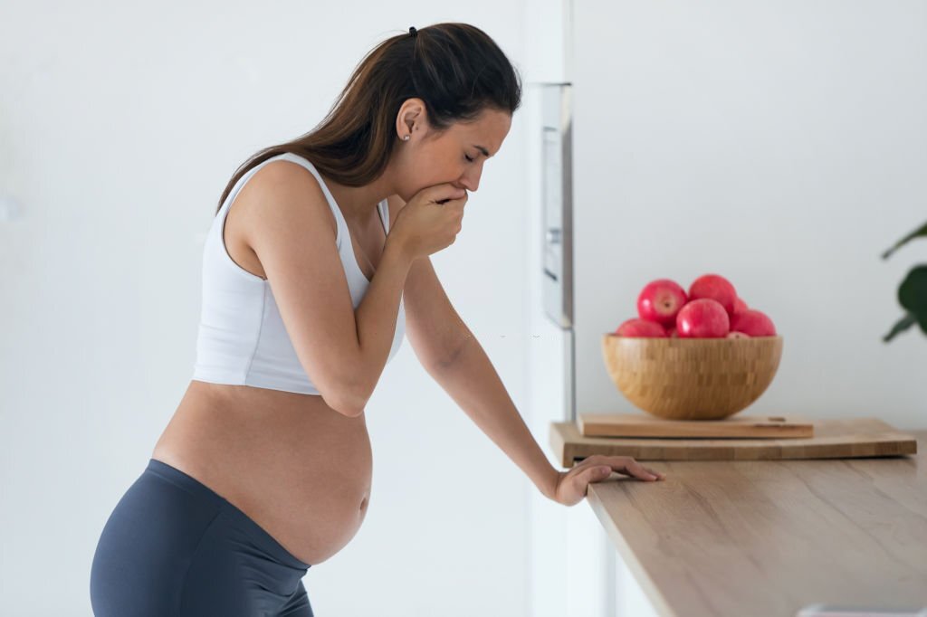 l'image représente une femme enceinte portant sans main à sa bouche pour montrer qu'elle a la nausée. vomissements