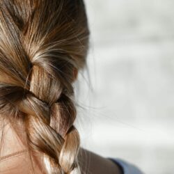 l'image représente une femme aux cheveux longs noués avec une tresse. été reflets cheveux
