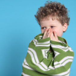 L'image représente un petit garçon qui se cache le visage. il a probablement peur qu'on lui fasse mal en désinfectant ses bobos.