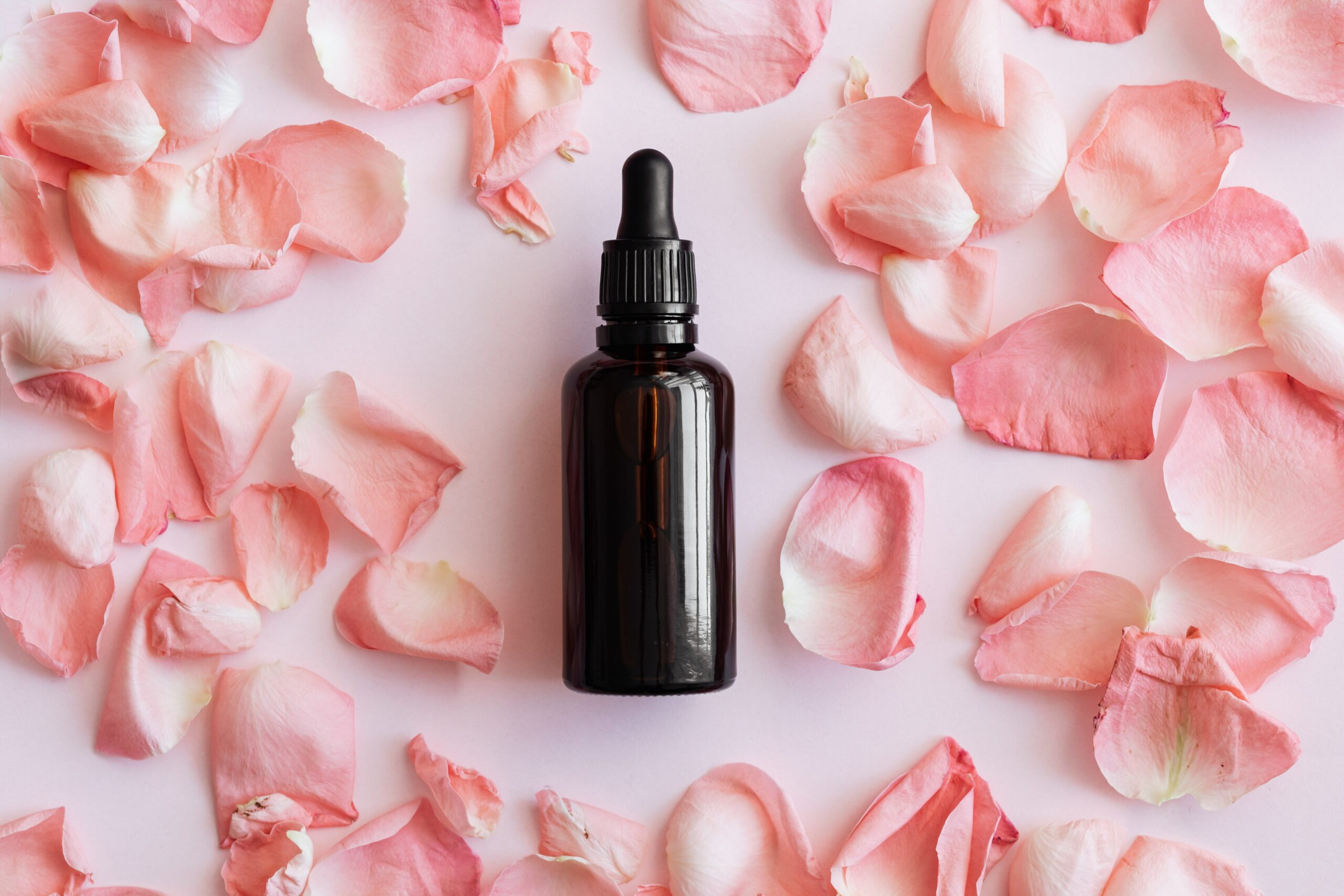 flacon d'huile végétale sur fond de pétales de rose – Soin naturel pour la peau et les cheveux.