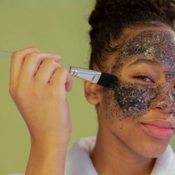Femme appliquant un masque hydratant scintillant sur une peau grasse à l’aide d’un pinceau, soin du visage pour rééquilibrer le sébum