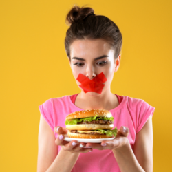 L'image représente une personne avec du scotch sur la bouche. elle tient un hamburger dans ses mains pour illustrer les aliments non autorisés dans le régime AIP. Le régime Paléo A.I.P dans la gestion des maladies auto-immunes