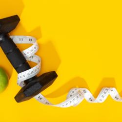 Haltère noire, pomme verte et mètre ruban symbolisant le rôle du sport et de l’alimentation dans l’augmentation du métabolisme.