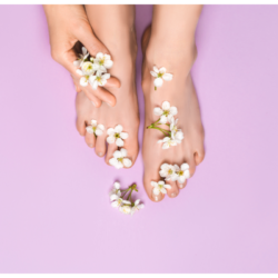 Pieds féminins ornés de fleurs blanches sur fond rose, symbolisant la douceur et l’hydratation après l’utilisation de masques de beauté pour les pieds.