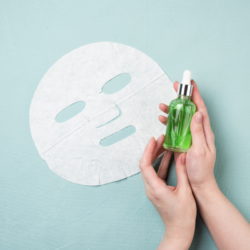L'image représente un masque à usage unique et les mains d'une personne qui tient un flacon de sérum. Très certainement un traitement pour apaiser la dermite séborrhéique. Comment soigner la dermite séborrhéique