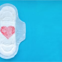 Serviette hygiénique avec un cœur rouge dessiné au centre sur un fond bleu. Mieux comprendre son cycle menstruel pour mieux le vivre