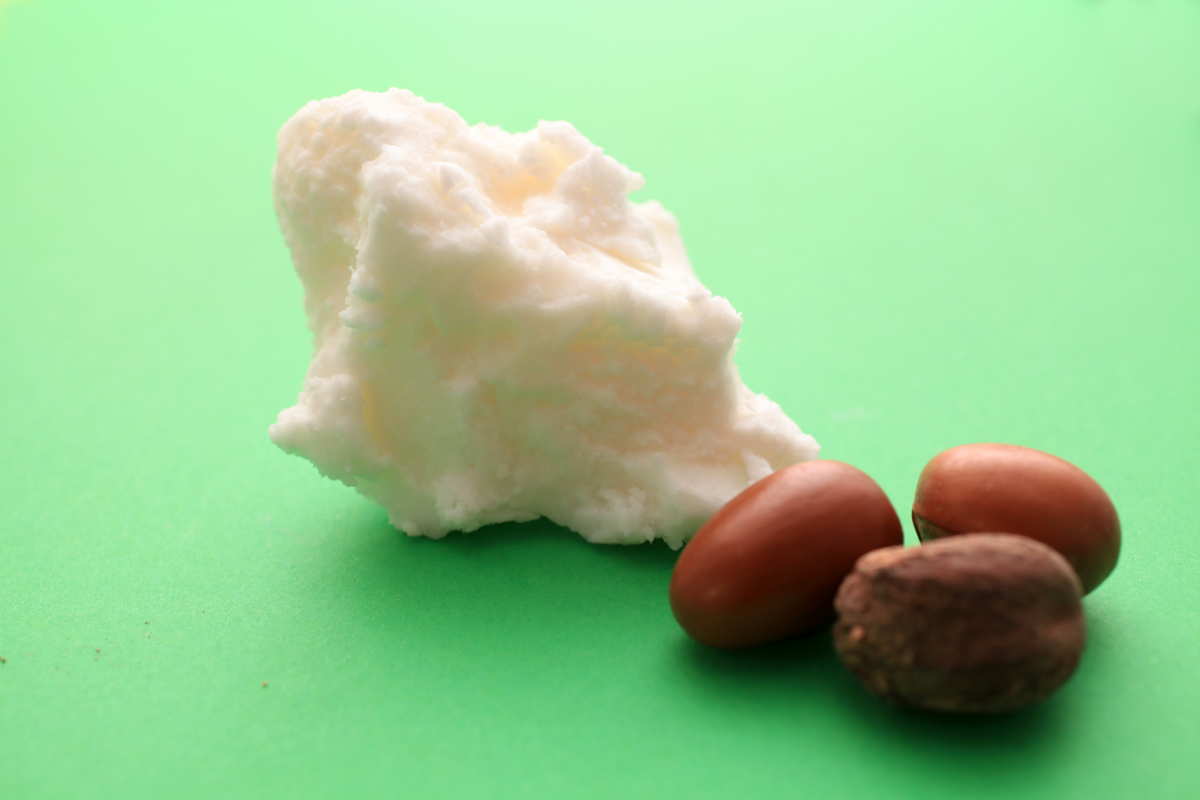 quels sont les bienfaits du beurre de karité. Li'mage représente du beurre de karité, des noix de karité sur un fond vert très vif.