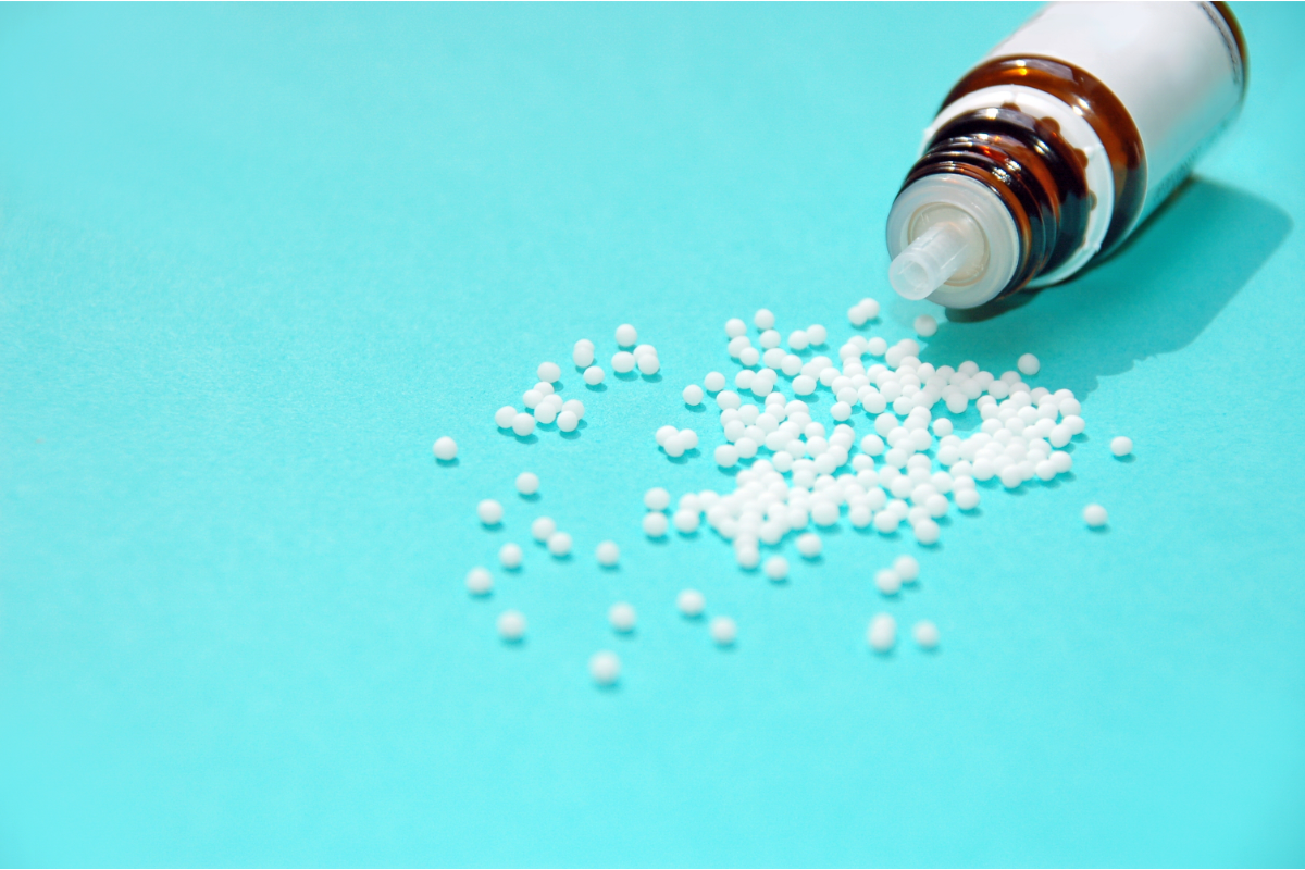 L'image représente un flacon de remèdes homéopathiques qui se déverse sur un fond bleu.