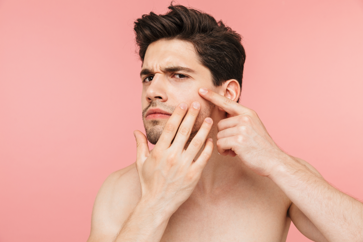 Curaspot à rincer, un homme devant son miroir en train de toucher ses boutons