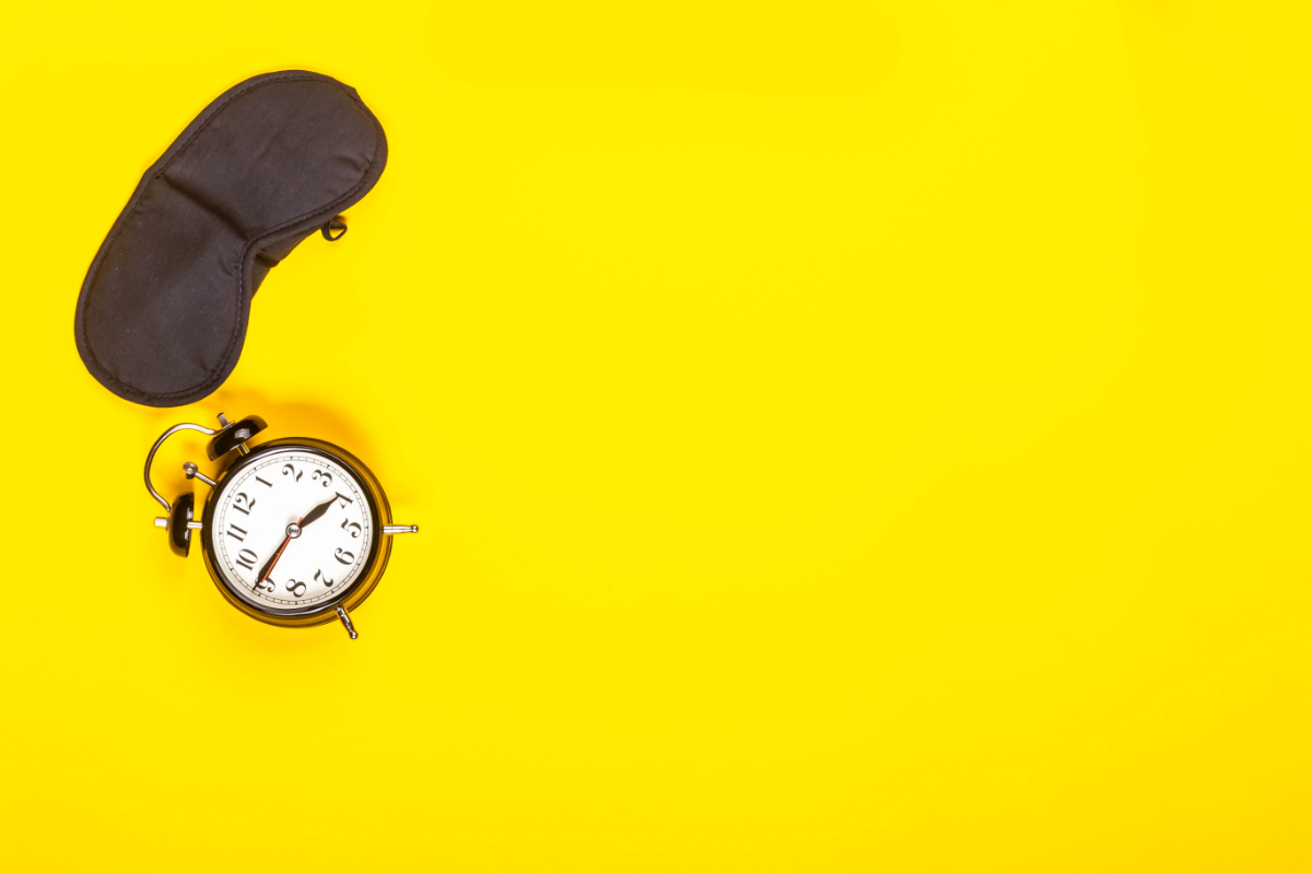 L'image représente un fond jaune vif sur lequel sont posées un réveil ainsi qu'un masque pour dormir pour les yeux. Comment Bien Dormir Lorsqu'il Fait Très Chaud La Nuit. Un bandeau cache yeux et un réveil sur fond jaune