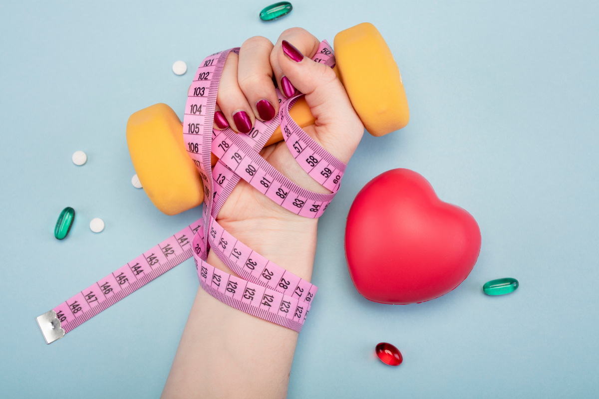 l'image représente une main qui tient une haltère jaune, avec un mètre ruban et un coeur rouge sur le côté.