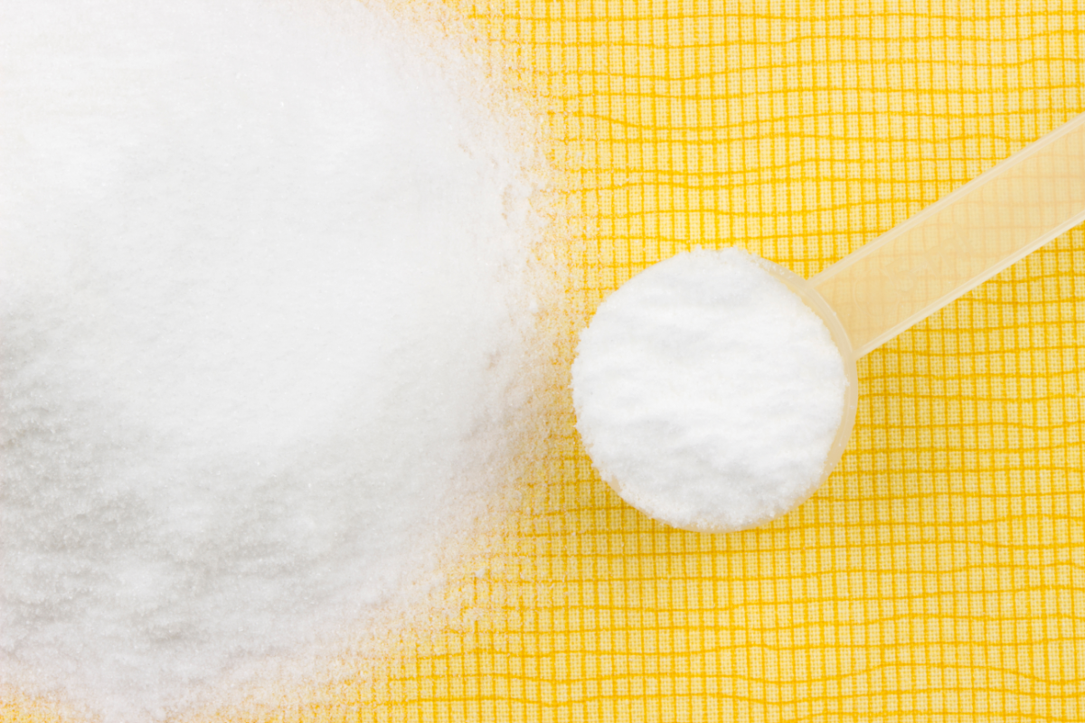 glutamine en poudre sur un fond jaune. un scoop de glutamine