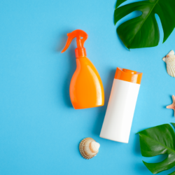 L'image représente différentes crèmes solaires, des coquillages et feuillages sur un fond bleu. Peut on fabriquer crème solaire maison