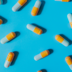 L'image représente des gélules bicolores bleu et jaune sur un fond bleu. spermidine fontaine de jouvence