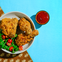 L'image représente une assiette de poulet frit sur fond bleu