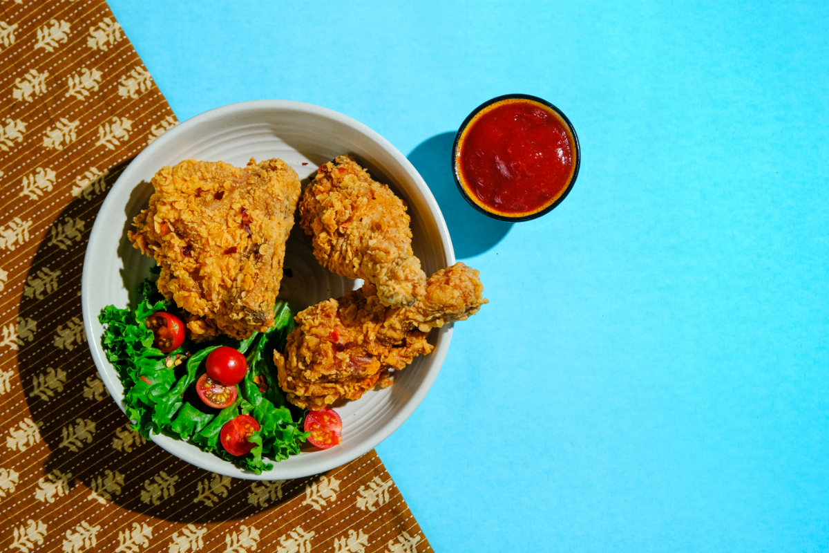 L'image représente une assiette de poulet frit sur fond bleu