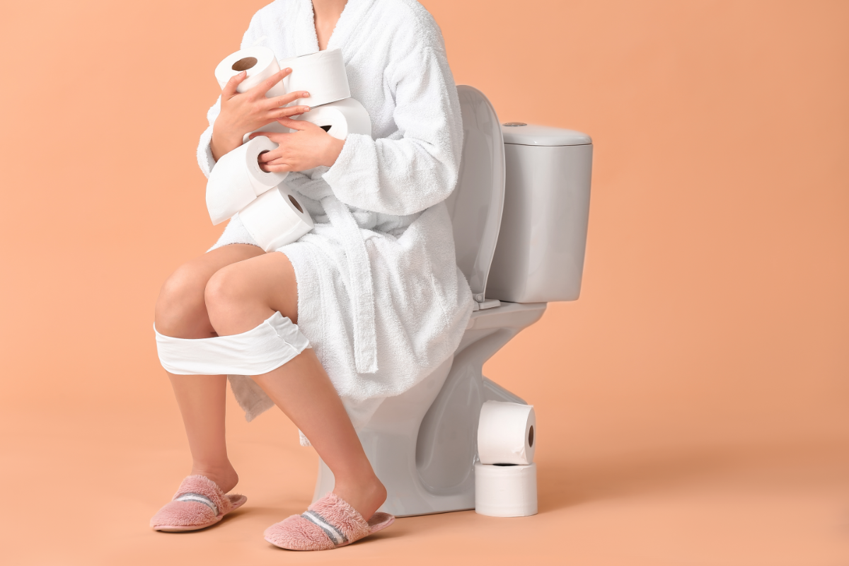 L'image représente une personne sur les toilettes avec plein de rouleaux de papier wc dans les bras. Elle a très certainement besoin de trouver une alternative naturelle au Smecta pour soulager rapidement sa diarrhée.