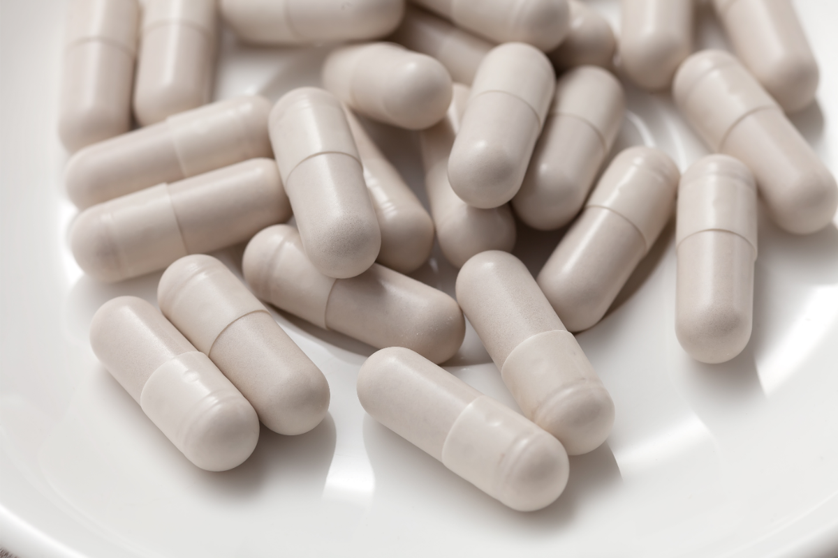 L'image représente des gélules qui se déversent sur un fond blanc.