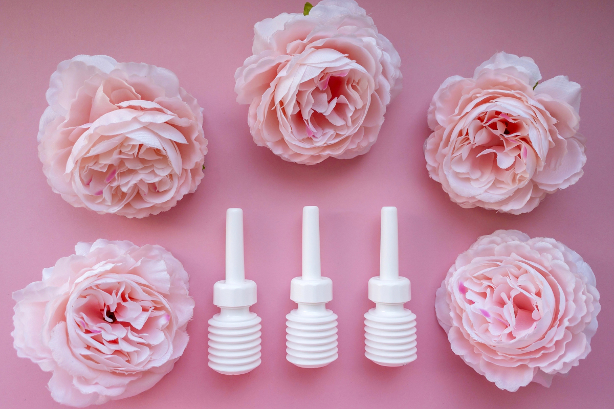 L'image représente un fond rose sur lequel sont posés des laxatifs de type dulcolax et des roses