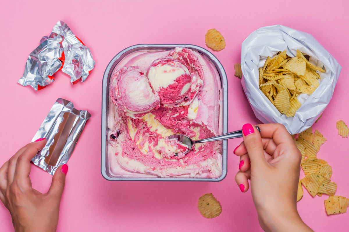 Femme mangeant de la glace, du chocolat et des chips – pulsions alimentaires liées au stress