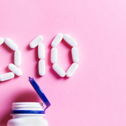 Image de comprimés formant les lettres Q10, représentant la coenzyme Q10, sur un fond rose, avec un flacon de suppléments ouvert en bas de l'image