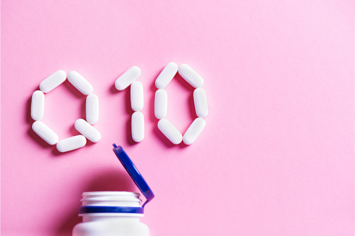 Image de comprimés formant les lettres Q10, représentant la coenzyme Q10, sur un fond rose, avec un flacon de suppléments ouvert en bas de l'image