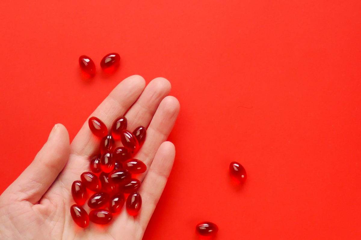 Complément d'Urolithine A en capsules rouges sur fond rouge.