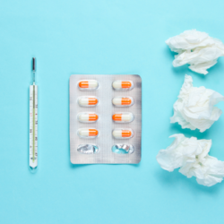mouchoirs usagers et pilules sur un fond bleu ciel