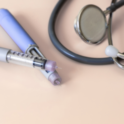 Deux stylos injecteurs de semaglutide (Ozempic) et un stéthoscope posés sur une surface beige.