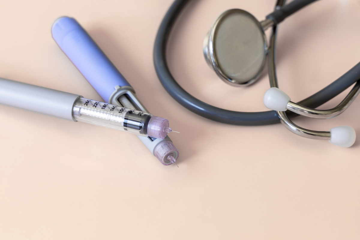 Deux stylos injecteurs de semaglutide (Ozempic) et un stéthoscope posés sur une surface beige.