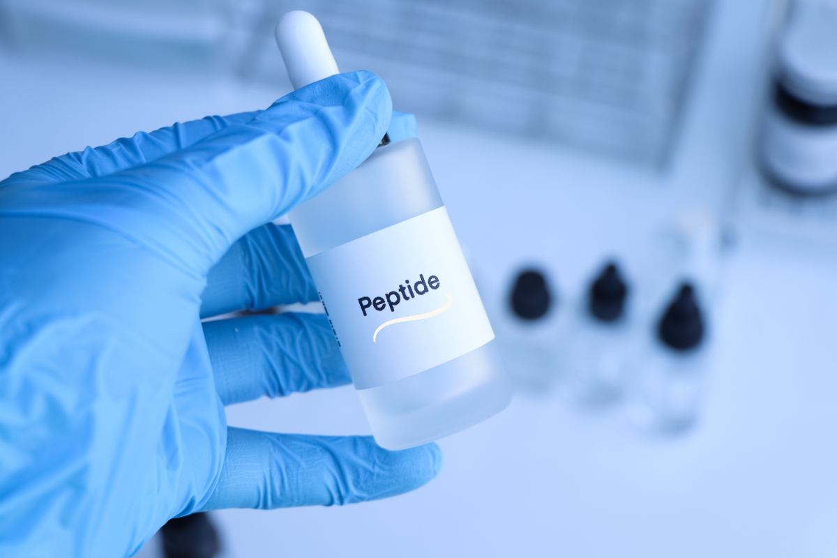 Flacon de peptide BPC-157 tenu par une main gantée en laboratoire, représentant les applications thérapeutiques du peptide BPC-157.