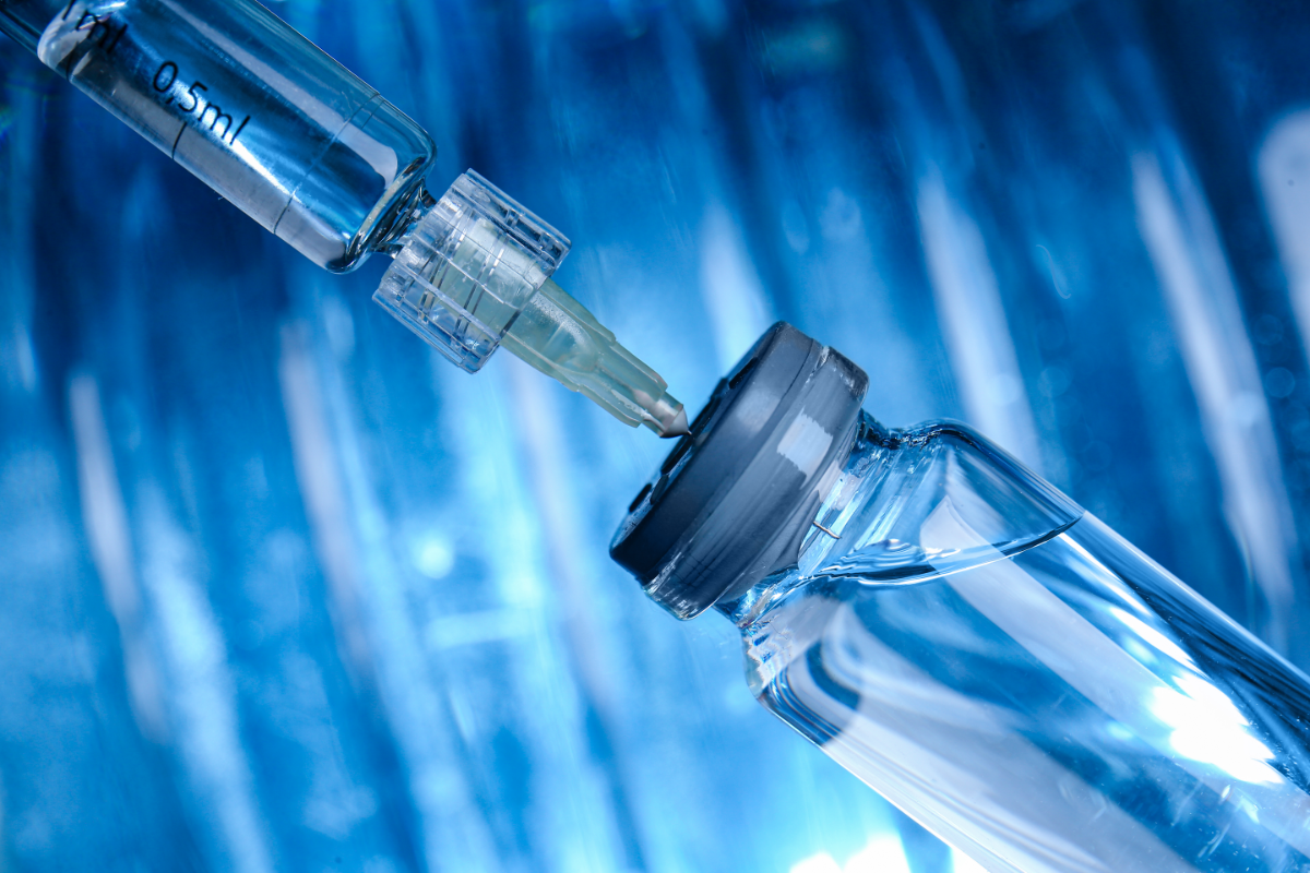 Gros plan sur une seringue de 0,5 ml insérée dans un flacon contenant du TB 500, un peptide utilisé pour ses propriétés régénératrices et anti-âge. L'image illustre l'importance de l'administration précise et stérile du TB 500 pour maximiser ses effets bénéfiques sur la réparation tissulaire et le rajeunissement des organes. Le fond bleu confère une atmosphère clinique, soulignant l'environnement médical dans lequel ce traitement innovant est utilisé.